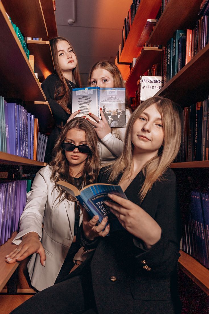 Amigas posando com livros entre as estantes da biblioteca